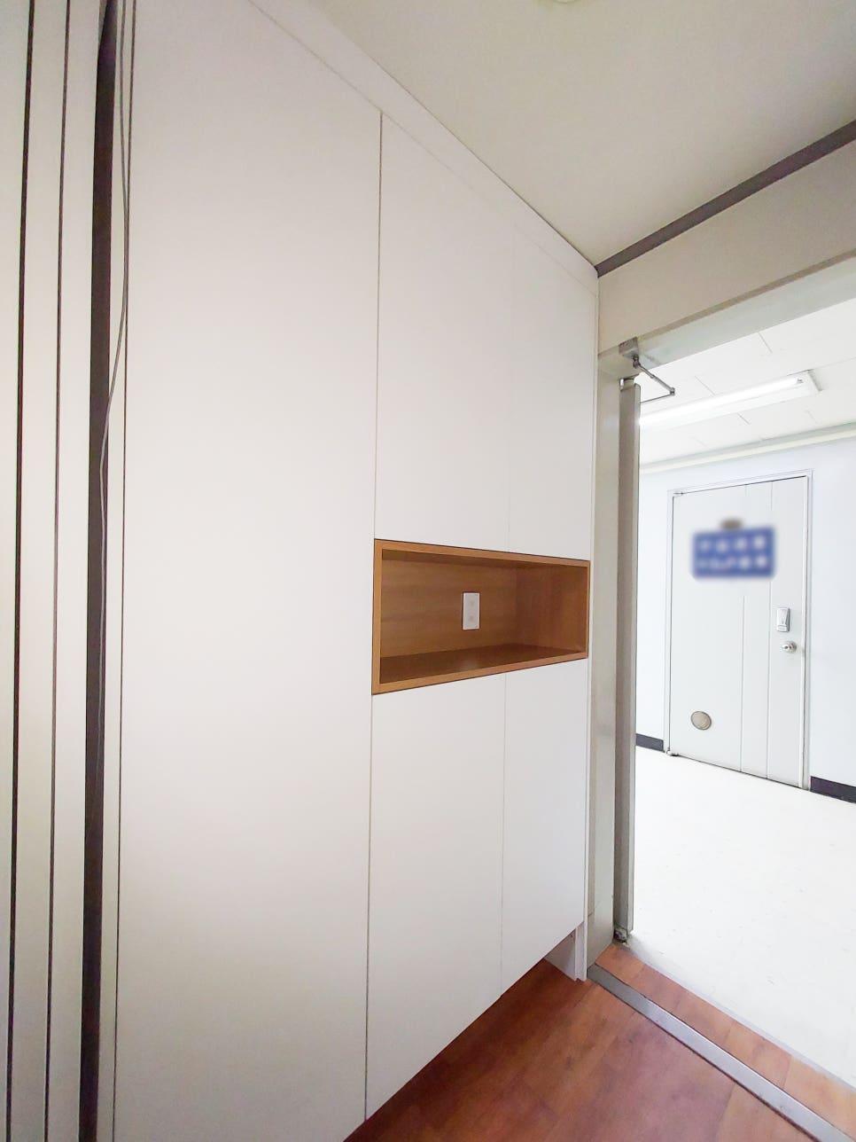 흰색 벽면에 나무색 내장 선반을 설치 중인 복도 공간