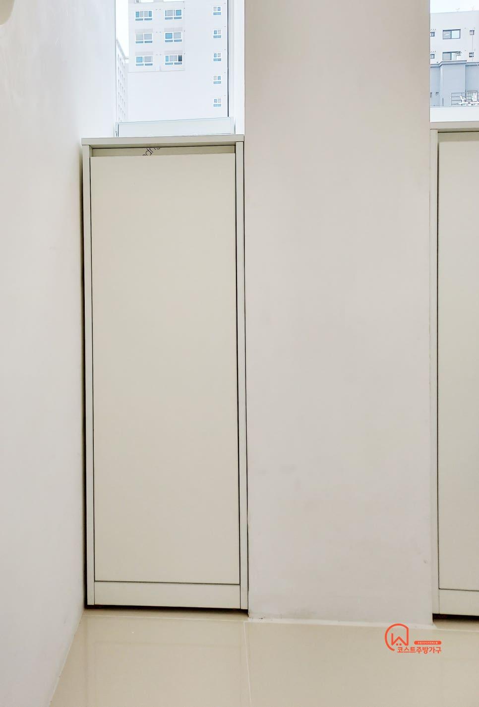창문 근처 벽면에 설치 중인 베이지색 수납장