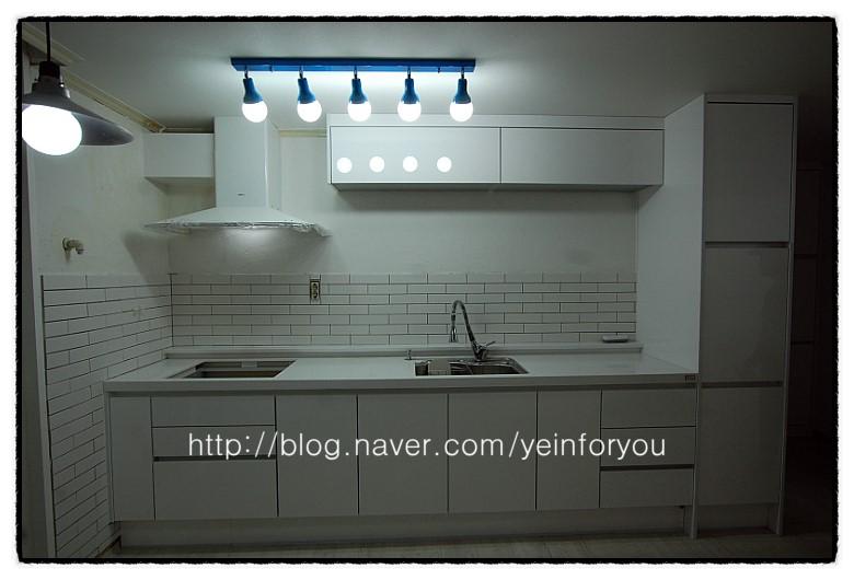 조명 아래 정돈된 싱크볼과 화이트 가구 공간