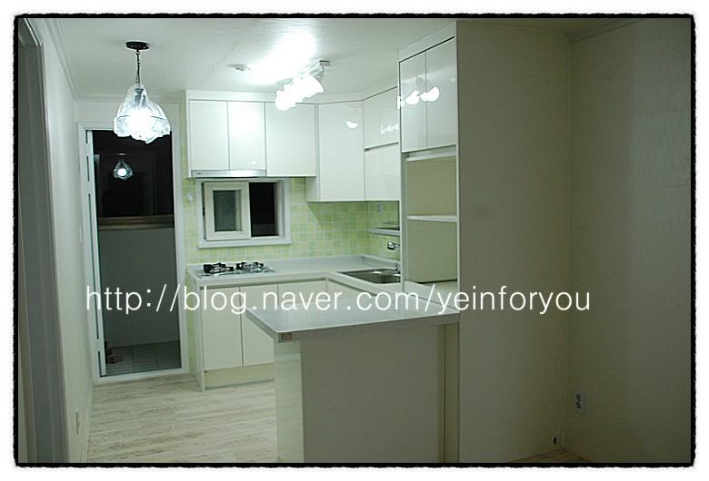 흰색 바닥재와 녹색 타일이 대비되는 조리 공간