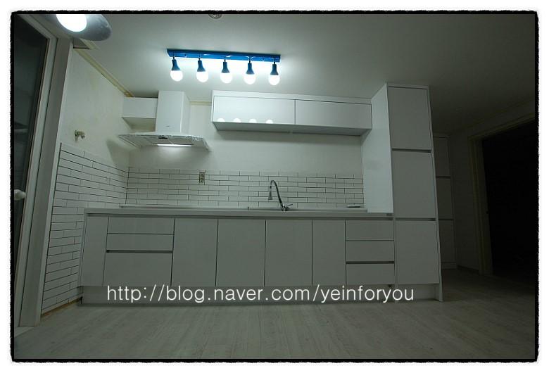 밝은 조명이 비추는 깨끗한 화이트 주방 가구
