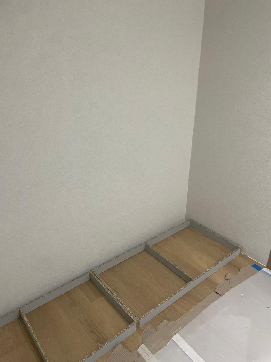 흰 바닥재 위에 설치 중인 목재 마루 구조물