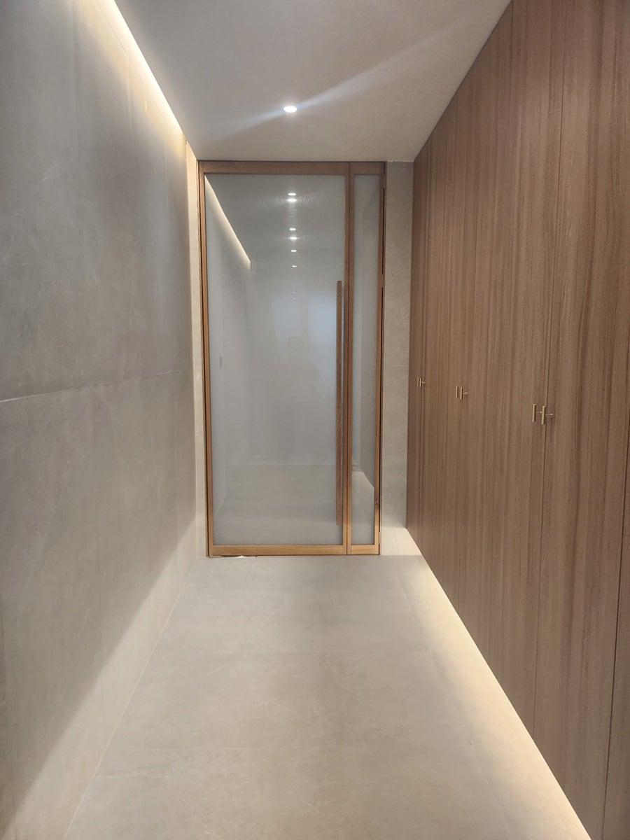 우드톤 붙박이장과 유리 슬라이딩 도어가 있는 복도