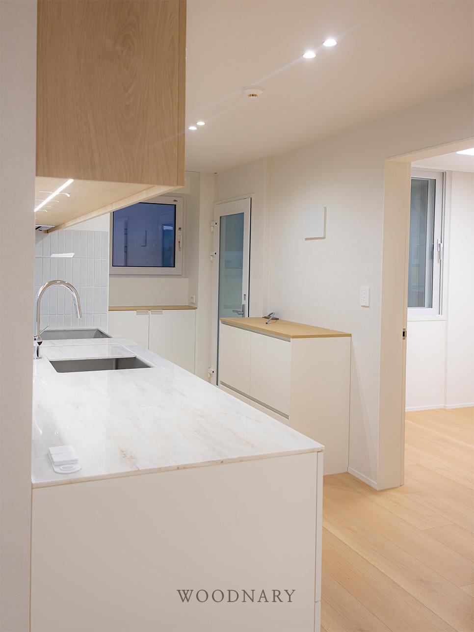 목재 마루 위로 펼쳐진 화이트 상판의 조리 공간
