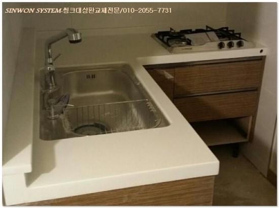 흰 상판 위에 설치된 은색 싱크볼과 수전