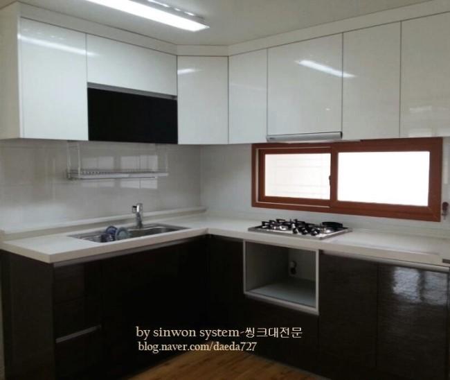 어두운 우드톤 수납장과 흰색 상판, 간접 조명이 있는 공간
