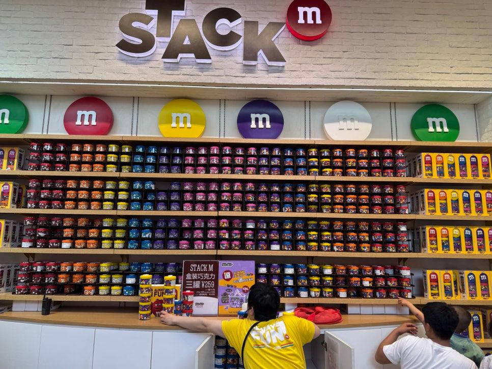 M&M 상품이 진열된 벽면 선반과 방문객