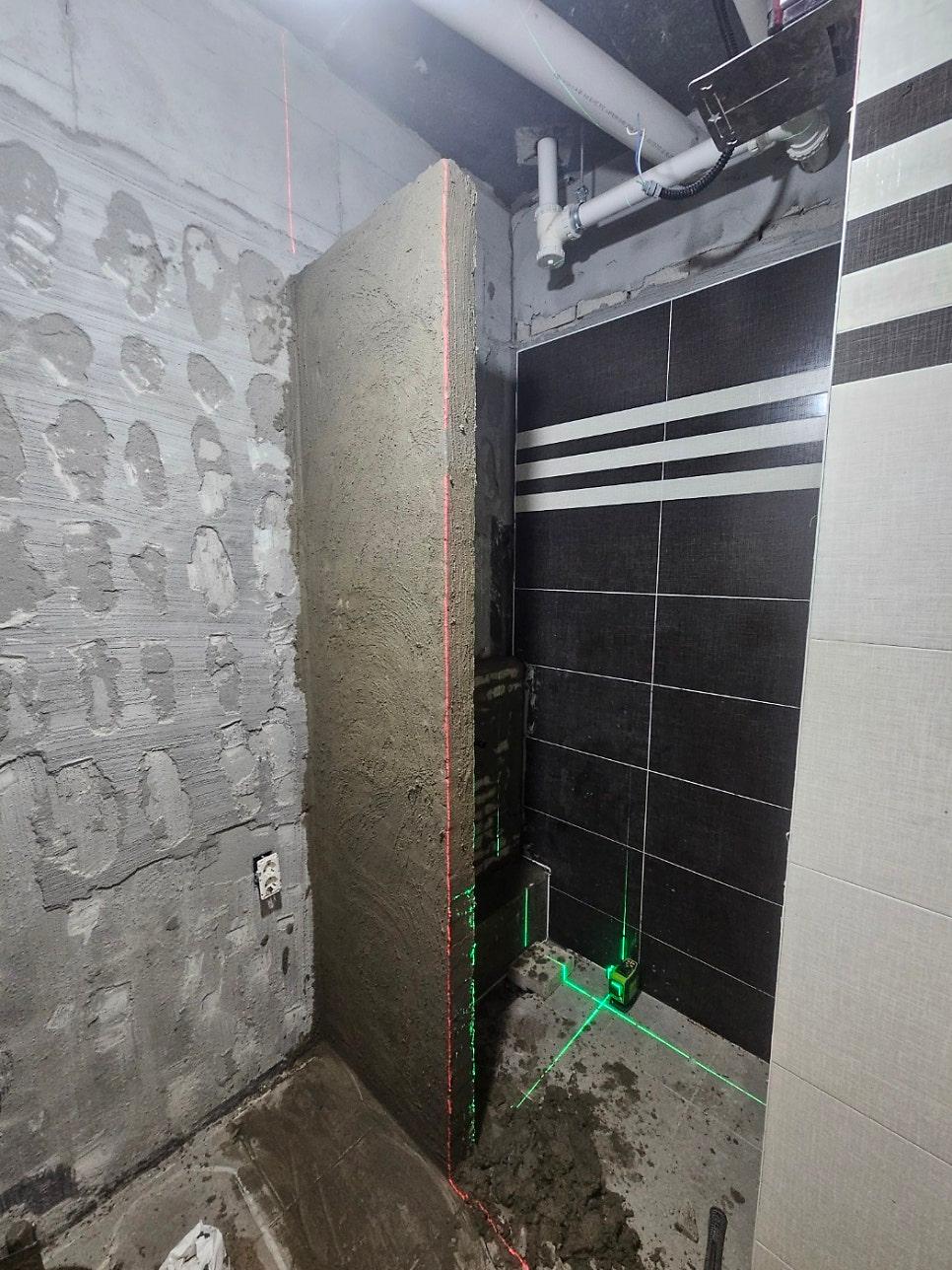 배관이 노출되고 벽면 타일 작업이 진행 중인 공간