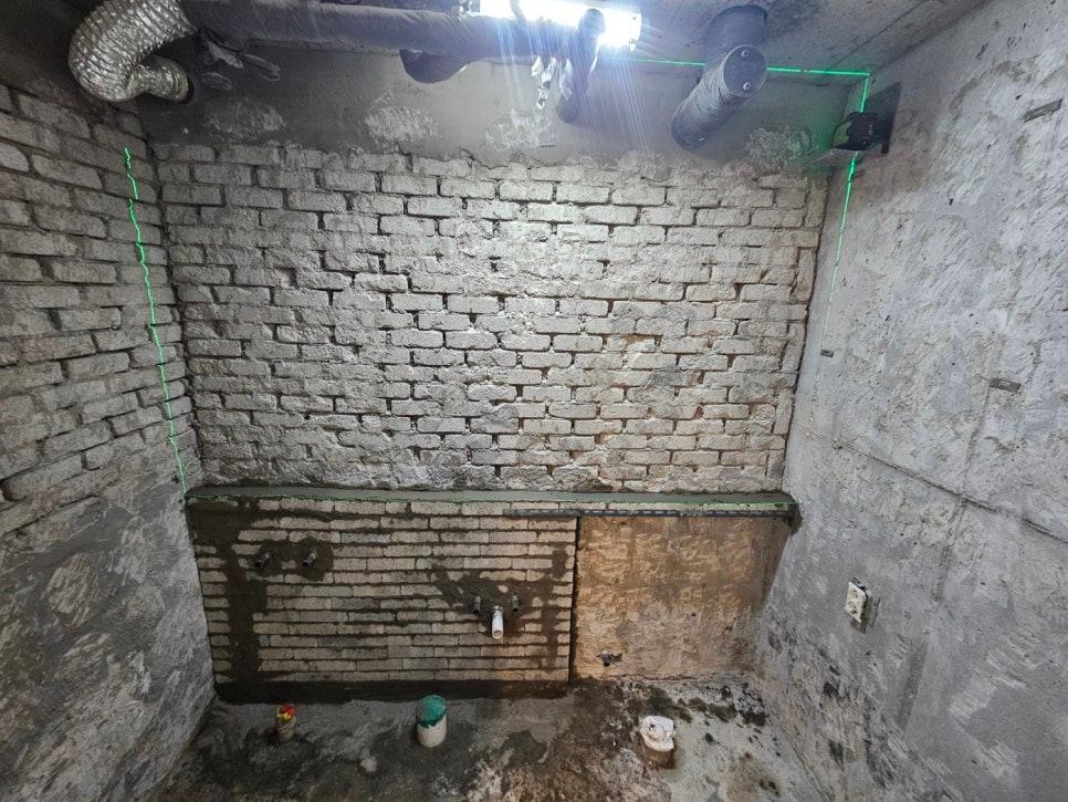 타일 철거 후 드러난 콘크리트 벽면과 배관