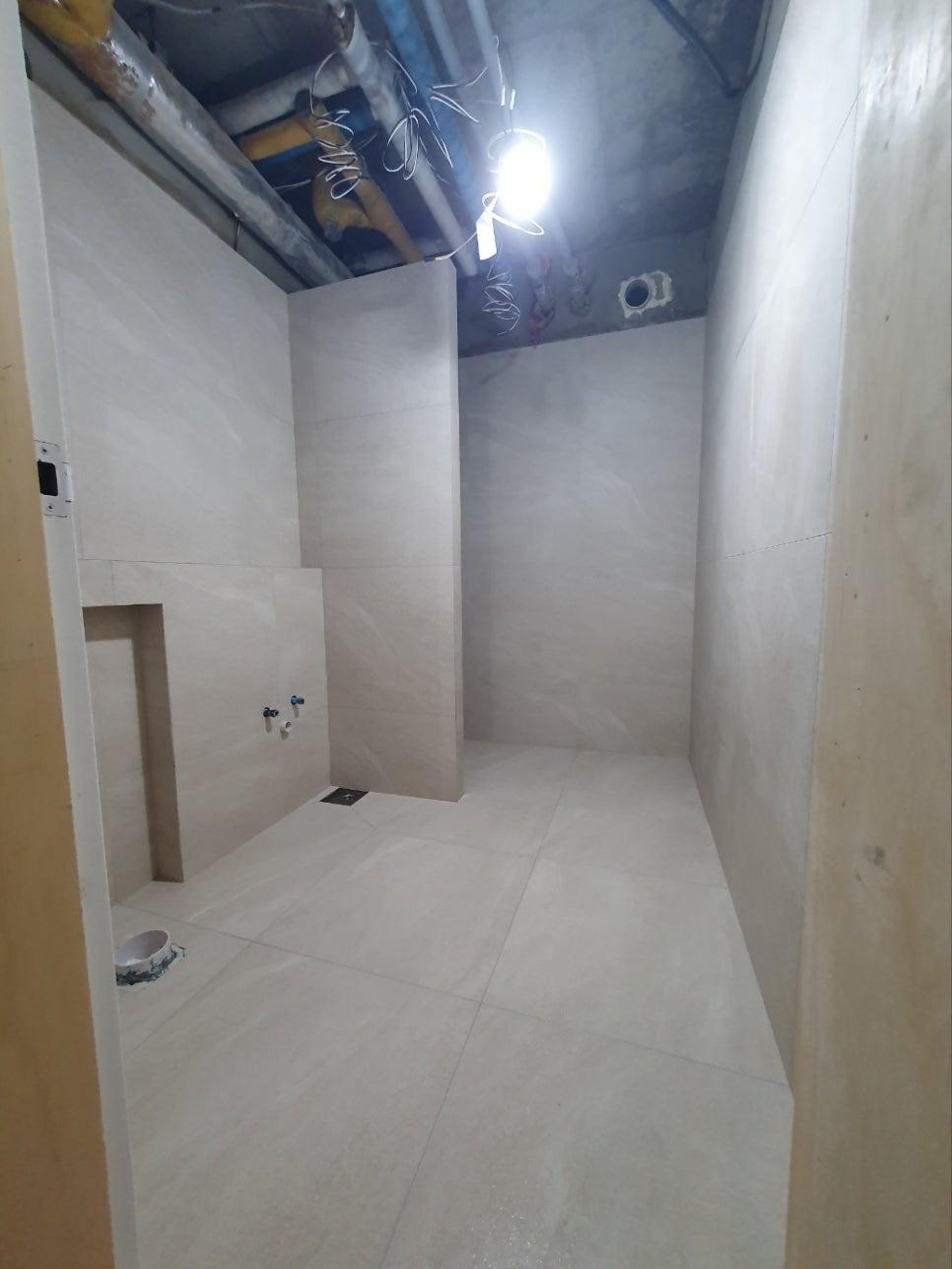 흰색 타일 마감과 천장 배관이 보이는 상태