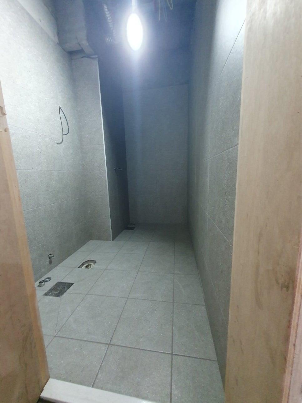 회색 타일 바닥과 천장 조명이 설치된 좁은 공간