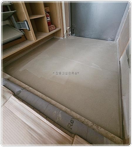 마감재가 깔린 바닥과 금속 문이 보이는 공간