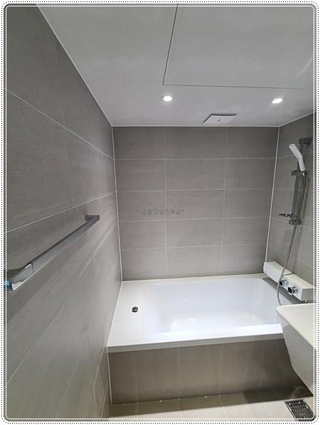 밝은 톤의 욕조와 샤워 설비가 배치된 장면