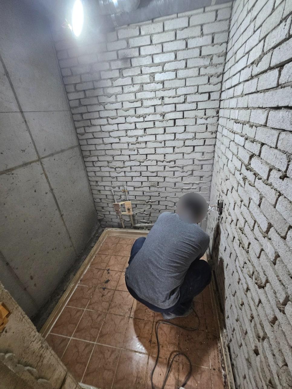 벽돌 벽과 타일 바닥이 보이는 공사 중인 실내