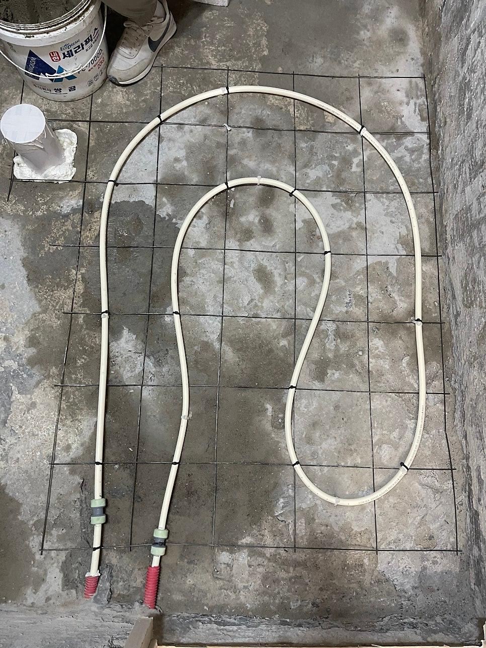 바닥에 S자로 배치된 흰색 PVC 난방 배관