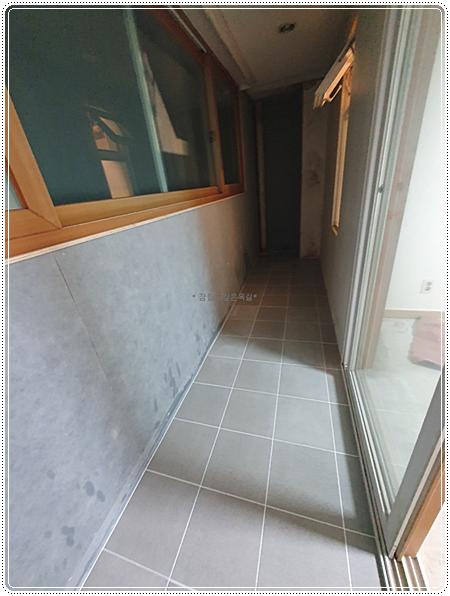 회색 타일로 마감 중인 복도와 유리문