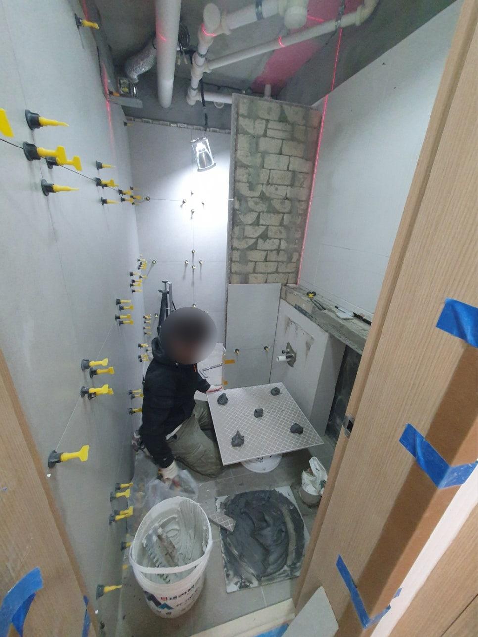 노란색 부품이 고정된 벽면과 타일 작업 중인 공간