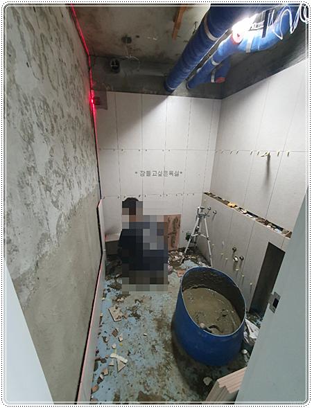 벽 타일 작업과 천장 파이프가 보이는 공사 현장