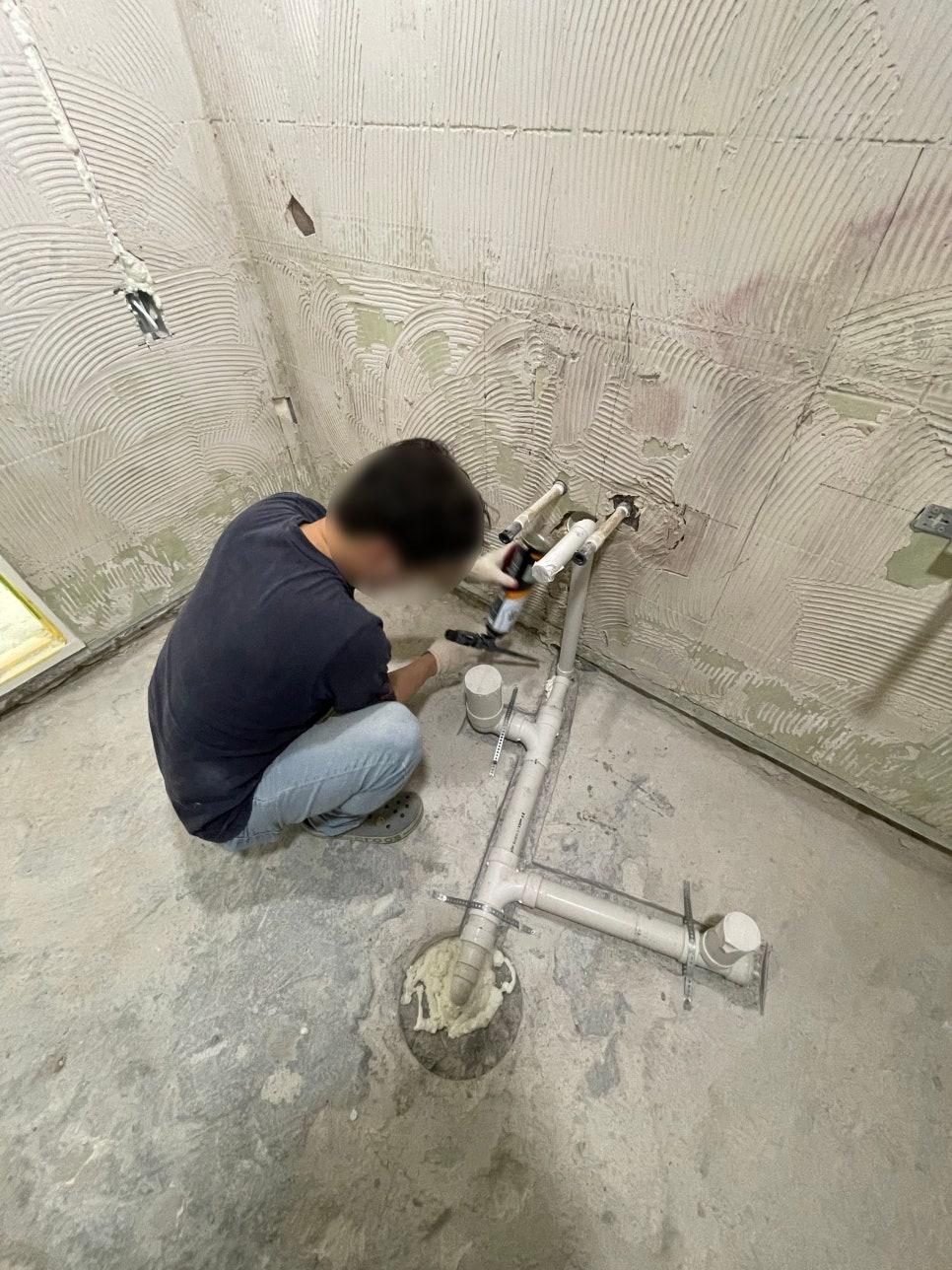 벽면 틈 사이로 설치 중인 흰색 PVC 배관
