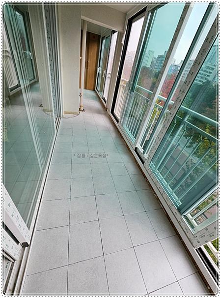 흰색 타일 바닥과 슬라이딩 창호가 보이는 베란다