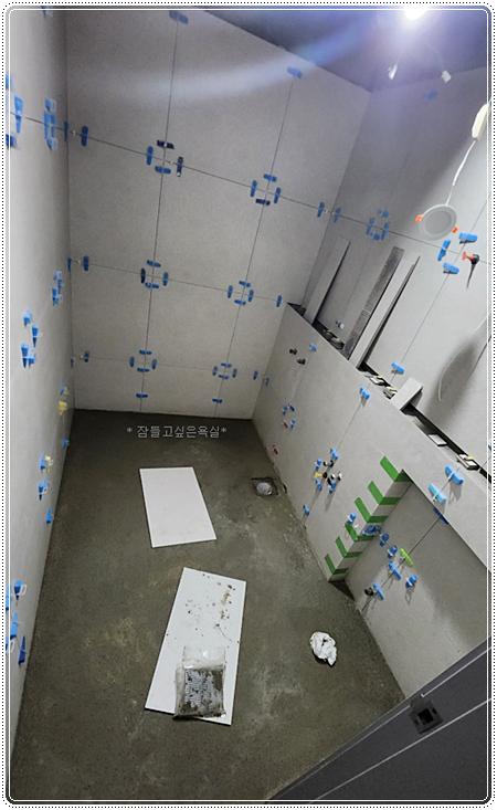 파란색 클립으로 타일을 고정 중인 벽면