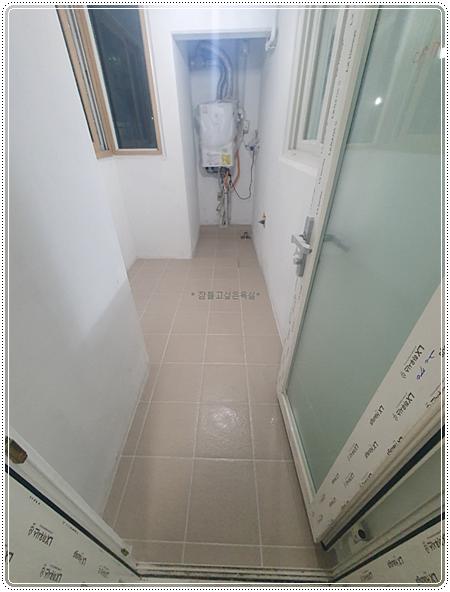베이지색 타일 바닥과 보일러 배관이 보이는 복도 공간