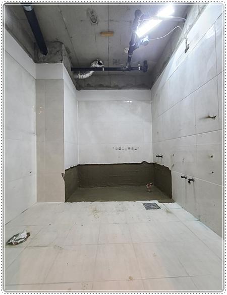 흰색 타일 시공이 진행 중인 욕실 내부 모습