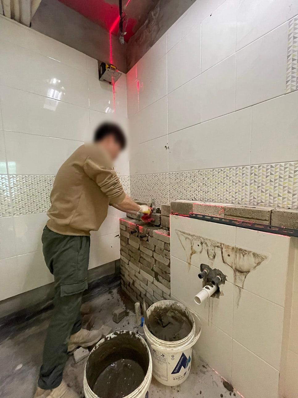 흰색 타일과 브릭 벽이 보이는 공사 중인 모습