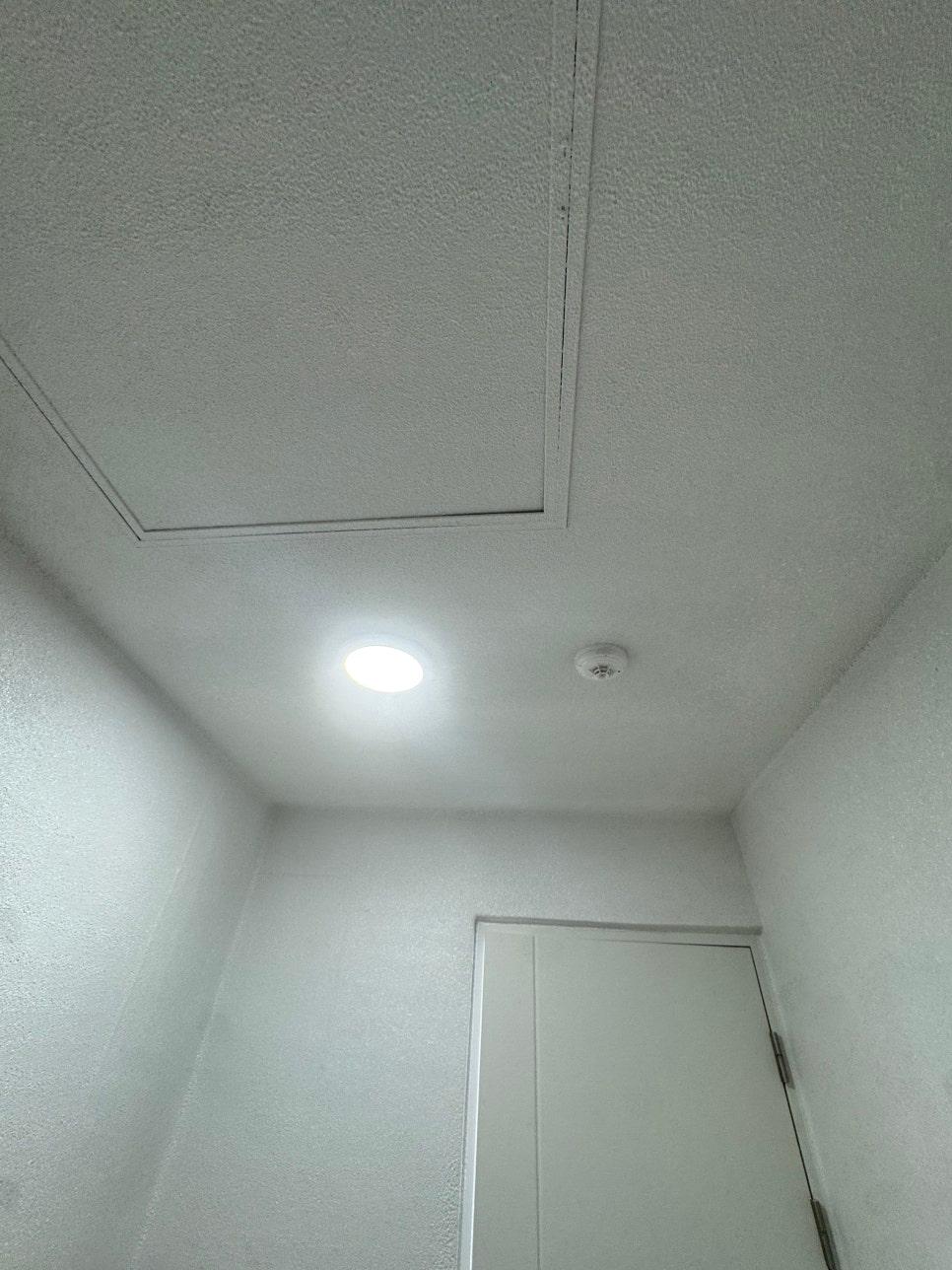 화이트 텍스처 마감 벽면과 원형 조명이 있는 복도