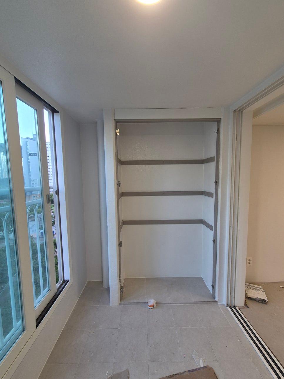 흰 벽면과 타일 바닥, 붙박이 선반 구조가 보이는 공간