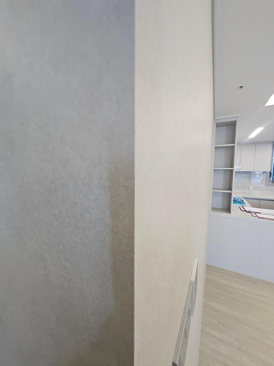 회색 벽면과 흰색 수납장이 맞닿은 주방 상판 근접샷