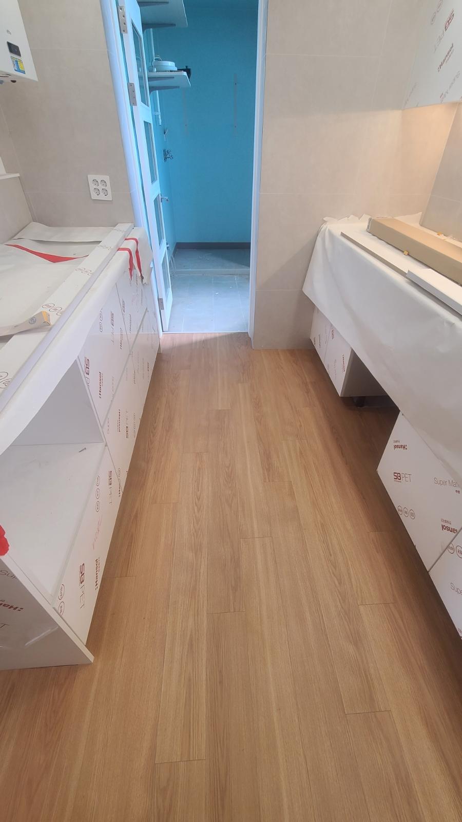 베이지색 타일 벽과 목재 마루가 이어지는 복도