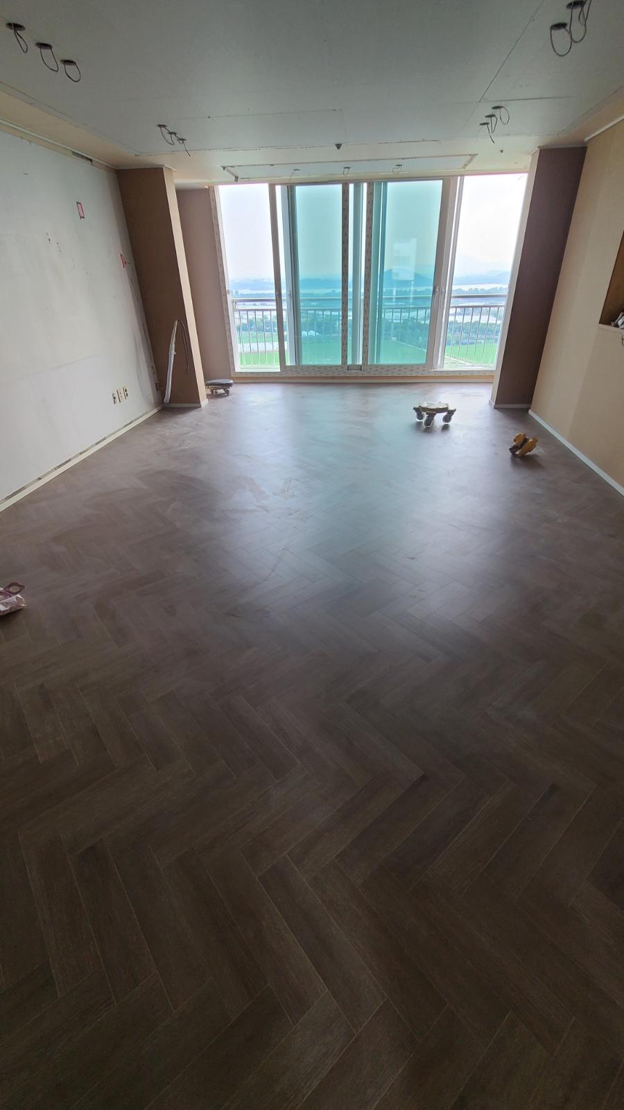 큰 창과 갈색 바닥재가 어우러진 넓은 실내 공간