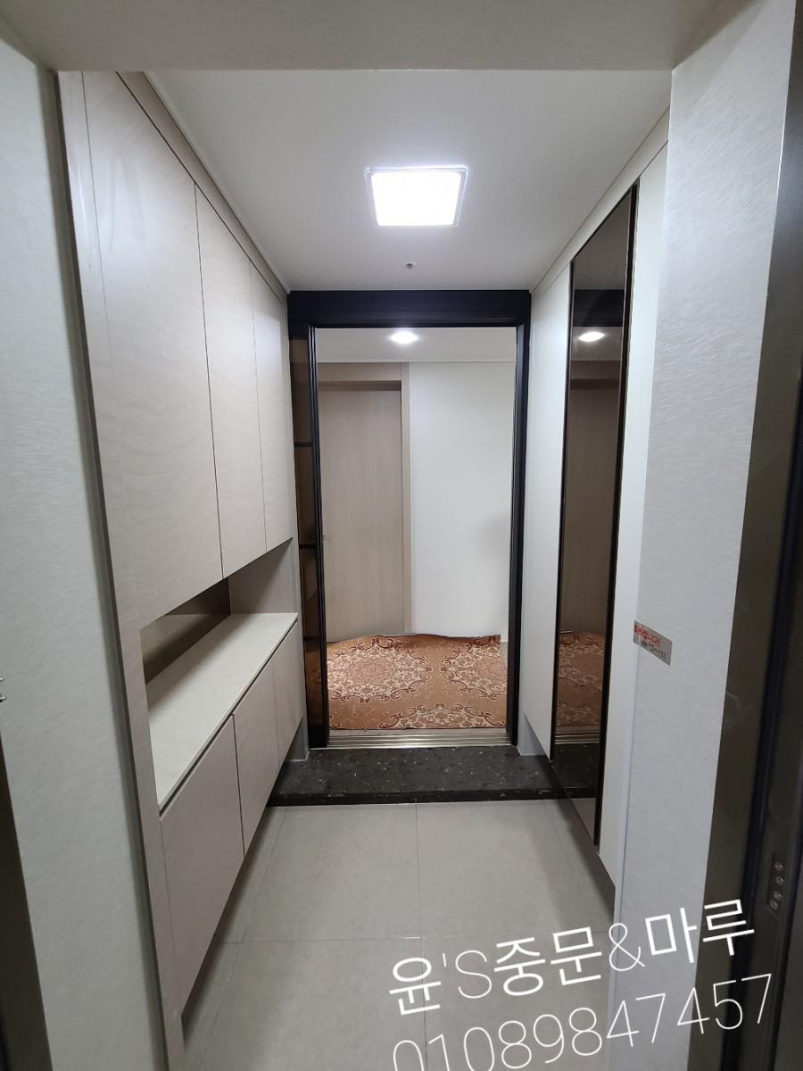 베이지색 수납장 배경에 설치된 블랙 프레임 유리 도어