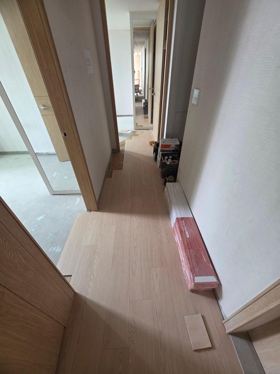 흰색 벽지와 목재 마루가 깔린 복도 공간