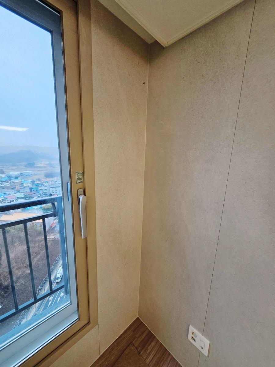 베이지색 벽면과 갈색 목재 패턴 바닥재가 만나는 창가