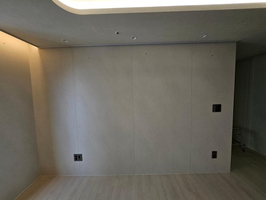 회색 벽면과 목재 바닥이 드러난 빈 실내