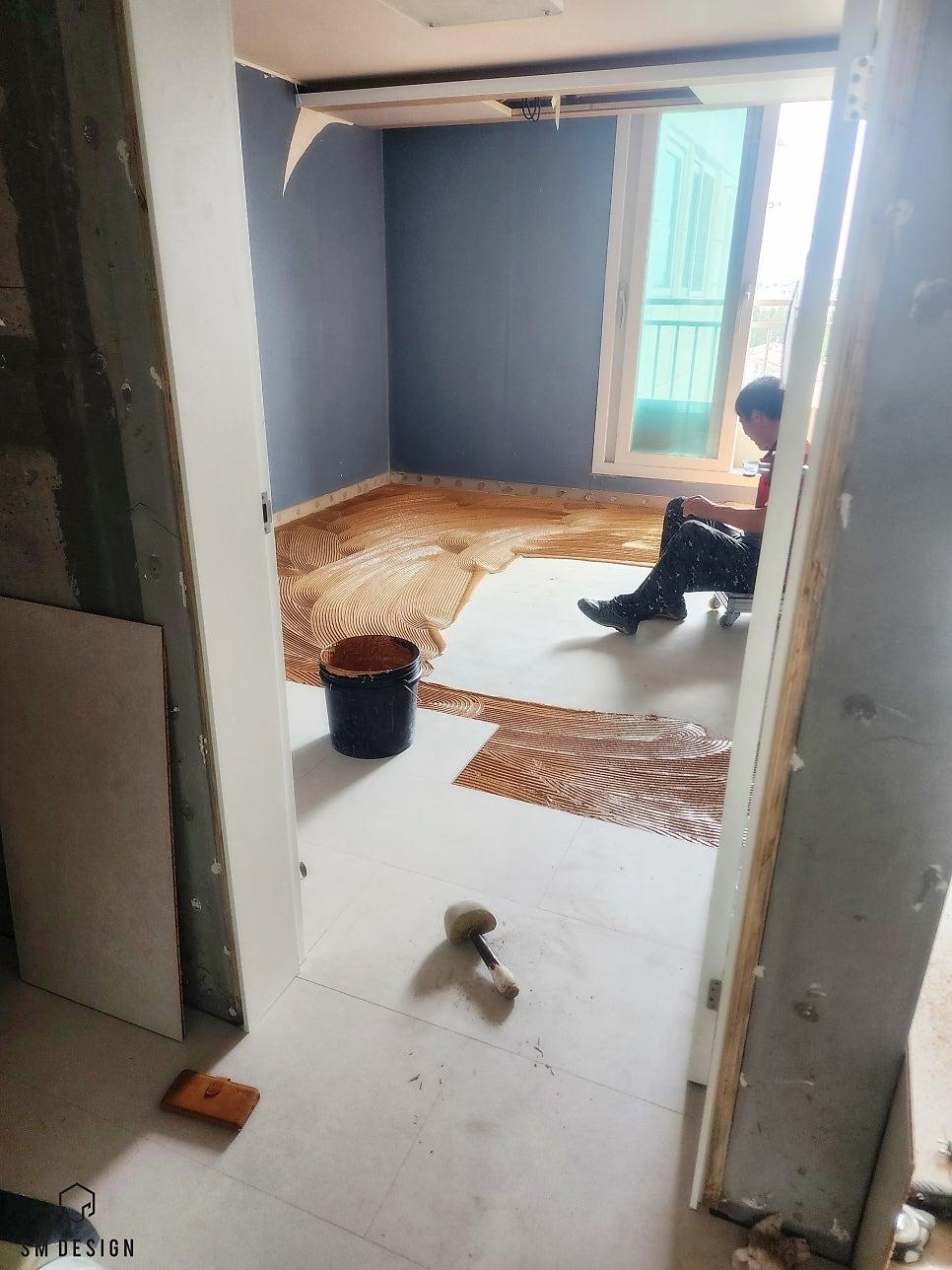 파란색 벽면과 바닥 접착제가 보이는 기초 작업 과정
