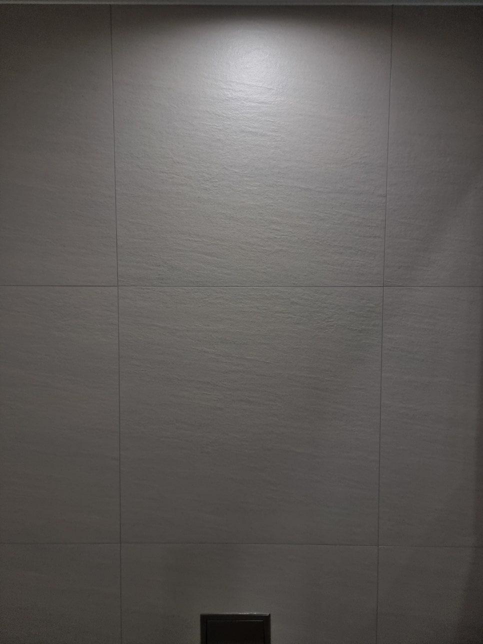 검은색 장치가 설치된 회색 타일 벽면