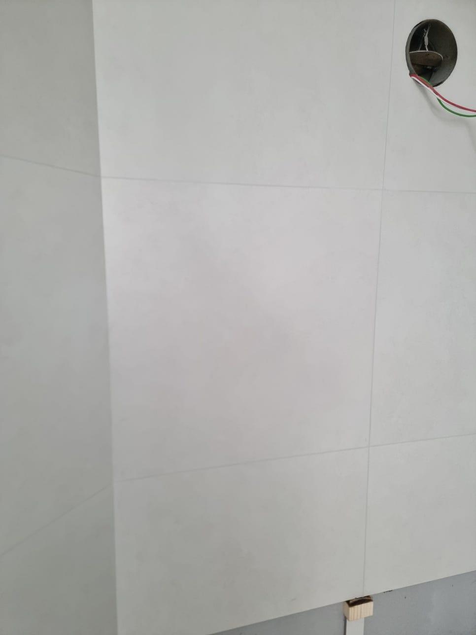 전선이 노출된 흰색 타일 벽면의 원형 구멍