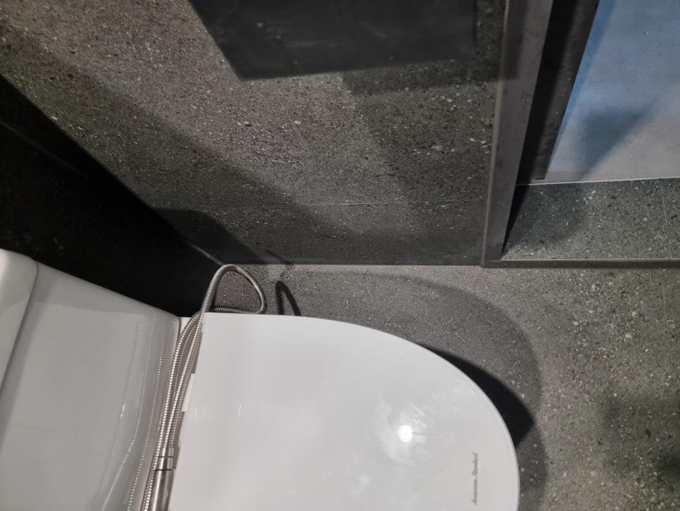 흰색 세면대와 검은색 타일 바닥 및 벽면의 근접 샷