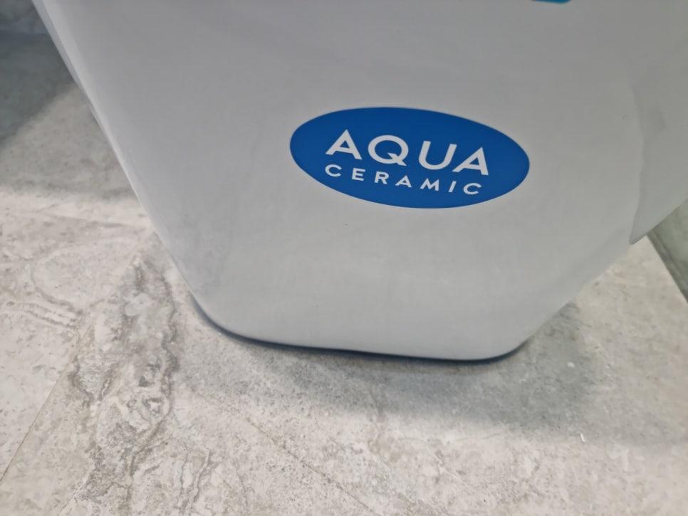 타일 바닥 위에 놓인 AQUA 브랜드 흰색 세라믹 물탱크