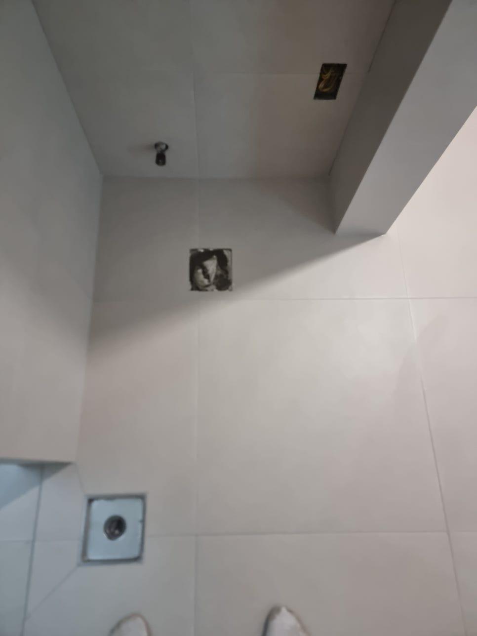수도꼭지와 배수구가 있는 흰색 타일 욕실의 시공 과정