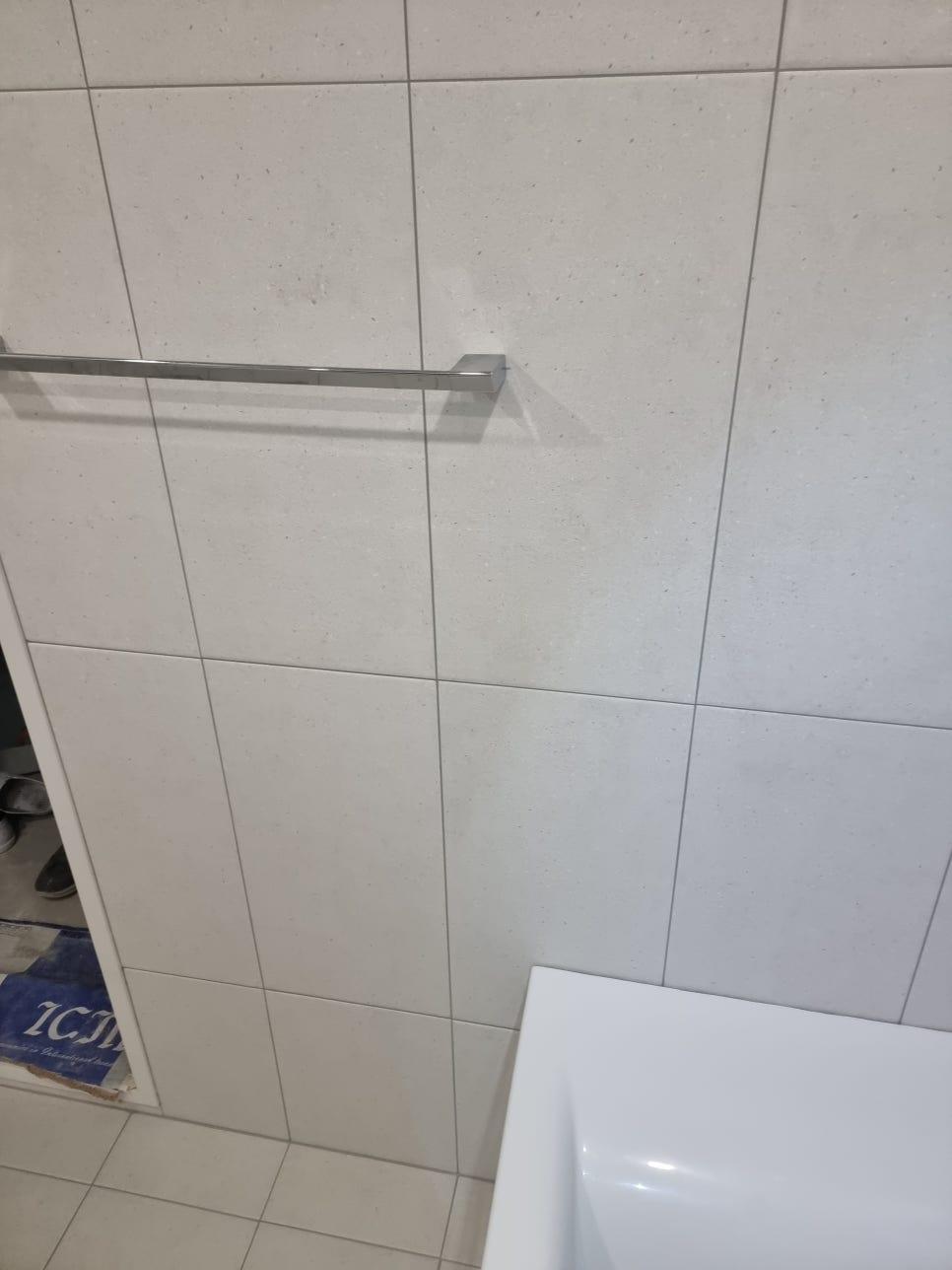 흰색 타일 벽면의 스테인리스 허리띠와 세면대 일부