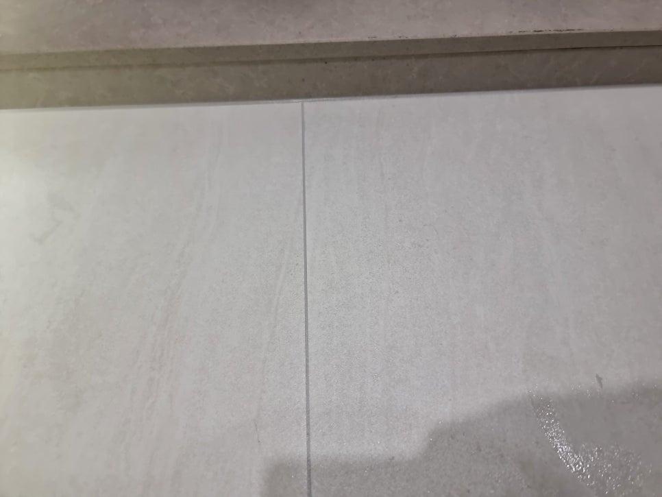 흰색 타일 바닥과 줄무늬 벽면 사이의 틈