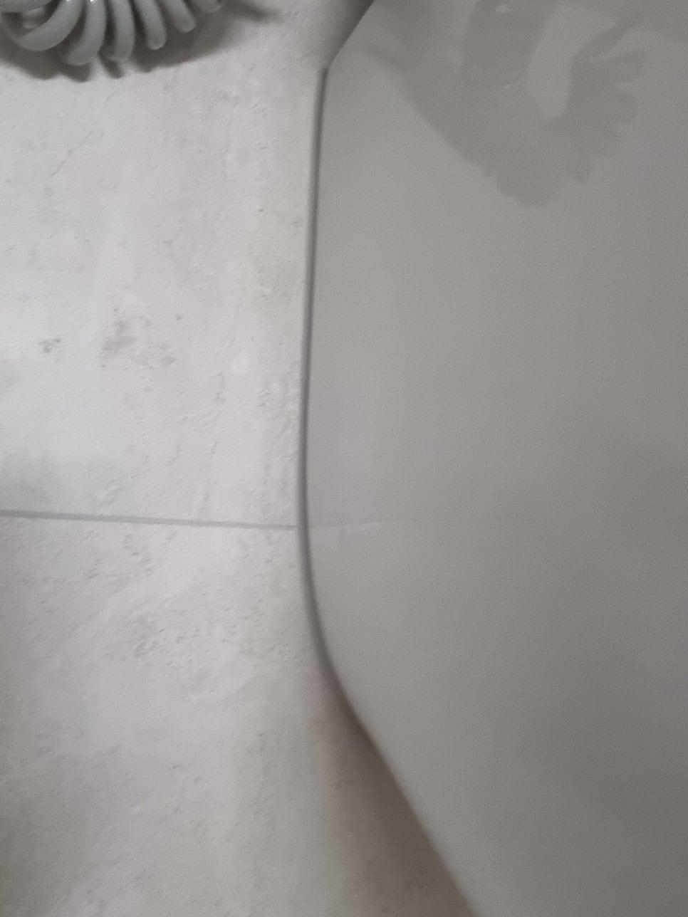 흰색 타일 벽면과 흰색 욕조의 접합부