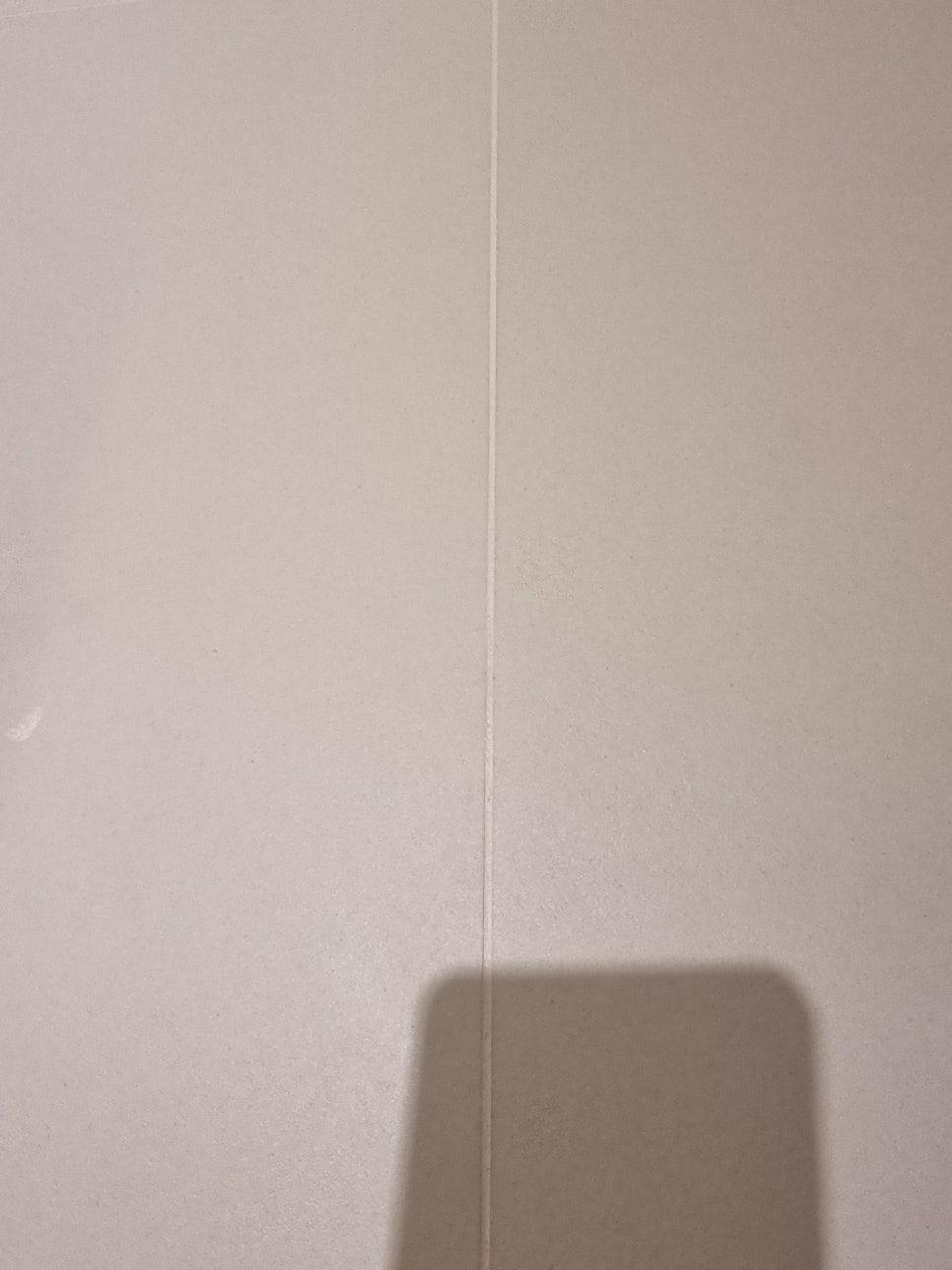 흰색 타일 벽면 중앙의 틈과 그림자