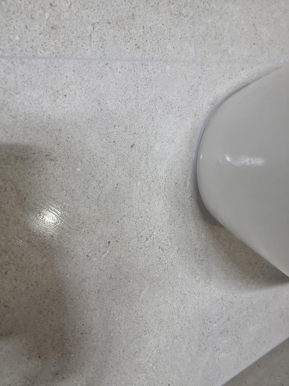 회색 타일 바닥과 세면대 일부가 보이는 모습