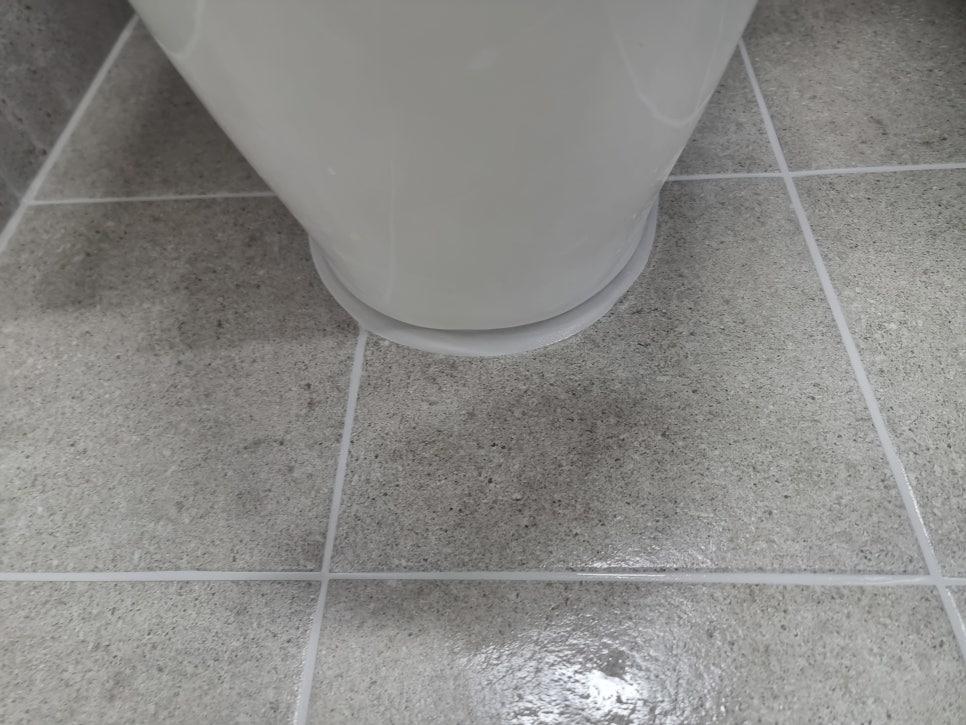 흰색 세면대 바닥 접합부와 회색 타일 바닥