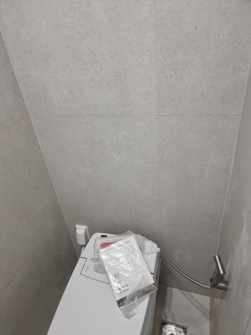 회색 타일 벽면과 세탁기가 놓인 공간